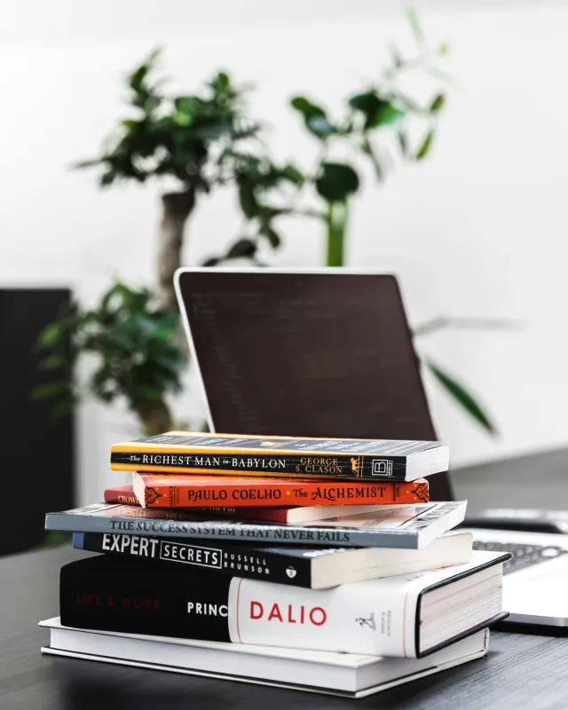 Business and thought leadership books beside a laptop